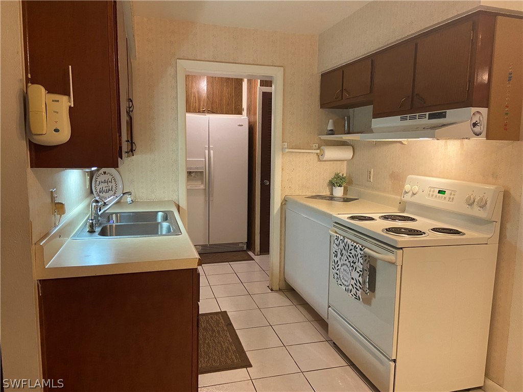 119 Apache Street Lehigh Acres, FL 33936 - Photo 13 of 29 a kitchen with a sink stove and refrigerator