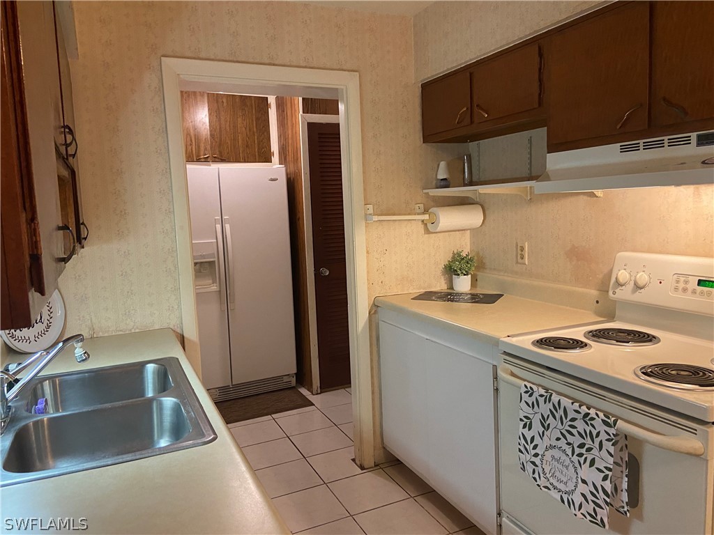 119 Apache Street Lehigh Acres, FL 33936 - Photo 17 of 29 a kitchen with stainless steel appliances granite countertop a sink stove and refrigerator