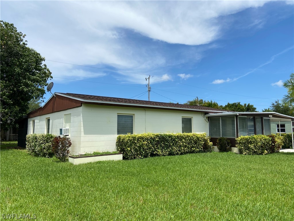 119 Apache Street Lehigh Acres, FL 33936 - Photo 3 of 29 a front view of a house with a garden