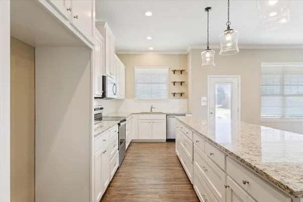 a large kitchen with granite countertop a large counter top space a sink stainless steel appliances and cabinets