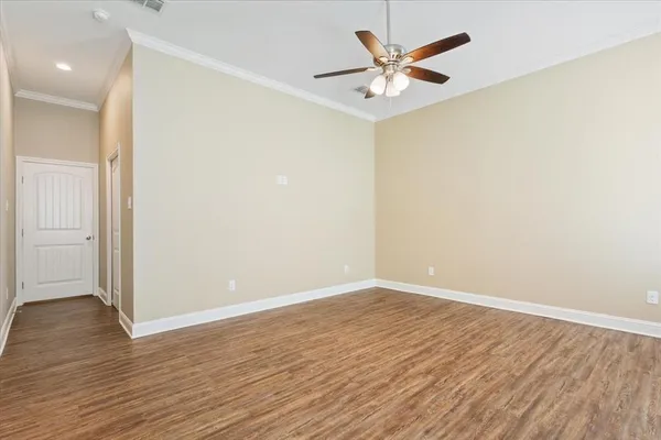 an empty room with wooden floor and a ceiling fan