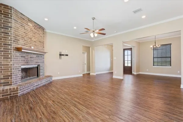 an empty room with wooden floor fireplace and windows