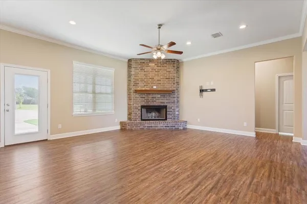 an empty room with wooden floor fireplace and windows