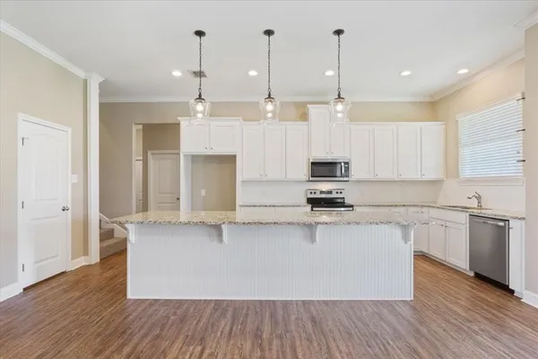 a view of a kitchen with kitchen island a counter top space stainless steel appliances and wooden floor