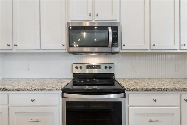 a kitchen with stainless steel appliances granite countertop white cabinets and a stove top oven
