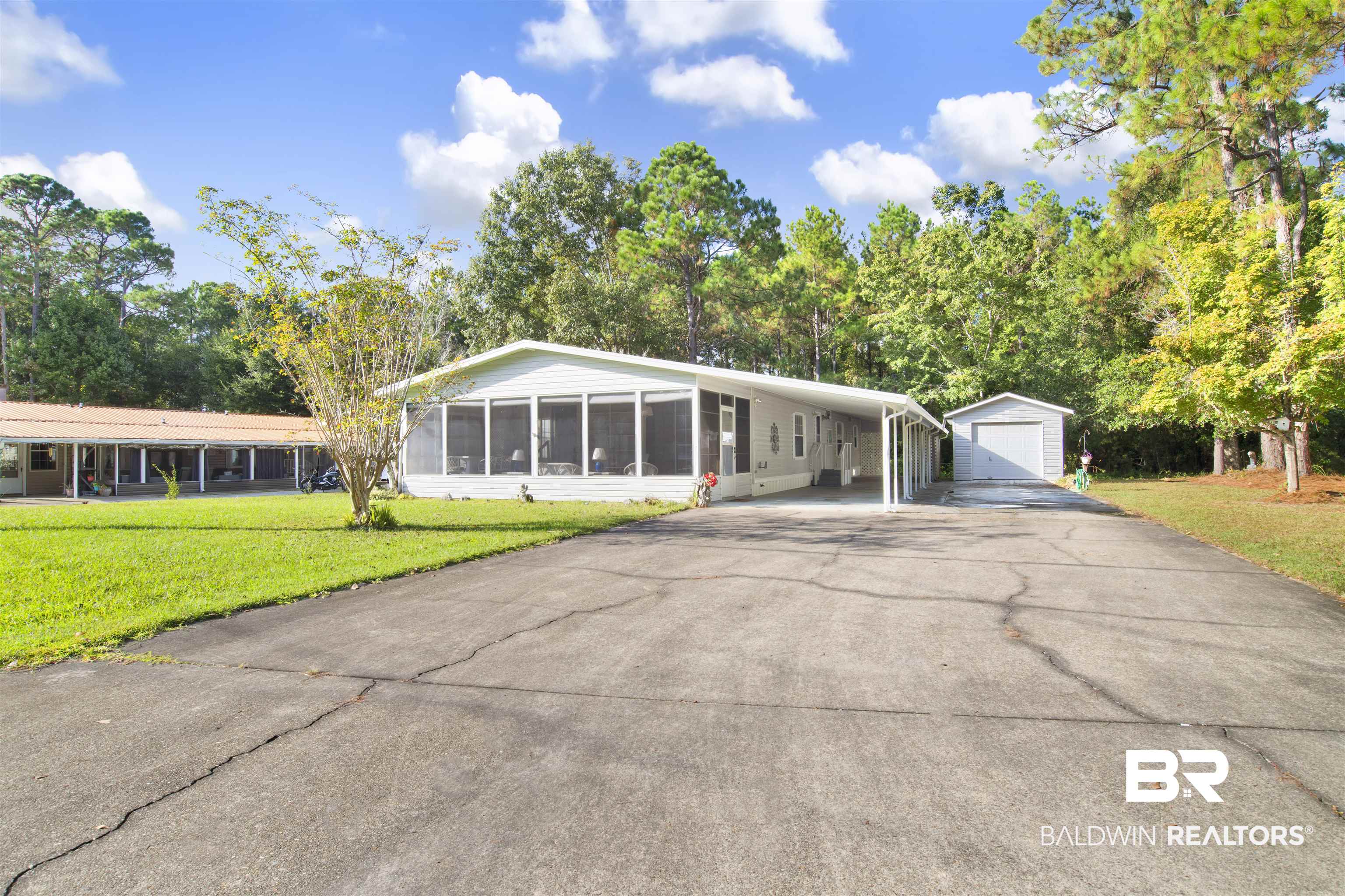 1216 Ridgewood Drive Lillian, AL 36549 - Photo 2 of 29 View of front facade featuring an outdoor structure, a front lawn, driveway, and a detached garage