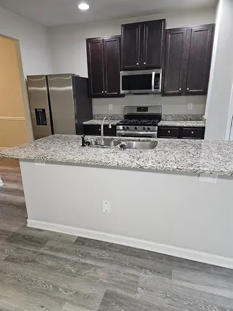 a kitchen with stainless steel appliances granite countertop a sink a microwave a refrigerator and cabinets