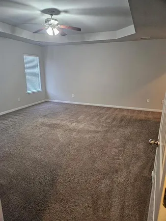 en empty room with windows and ceiling fan