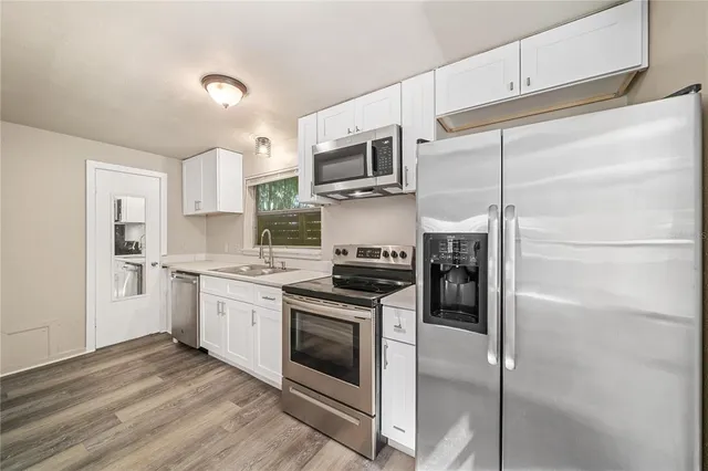 a kitchen with stainless steel appliances white cabinets and a stove top oven