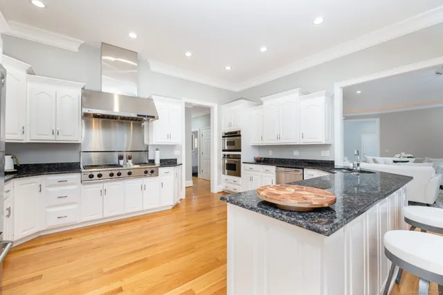 a kitchen with granite countertop kitchen island stainless steel appliances a sink and a refrigerator