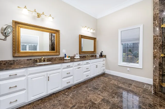 a bathroom with double sink large mirror a vanity and a window