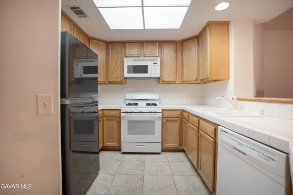 a kitchen with stainless steel appliances granite countertop a refrigerator stove top oven and sink