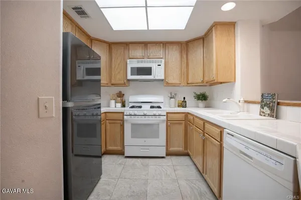 a kitchen with a sink cabinets stainless steel appliances and a window