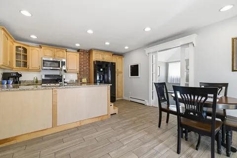 a kitchen with stainless steel appliances kitchen island granite countertop a table chairs sink and cabinets