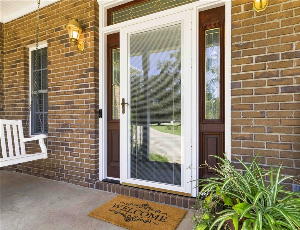 An inviting front entry features a glass storm door framed by decorative brick walls.
