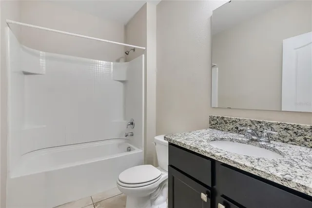 an empty room with a chandelier fan and windows