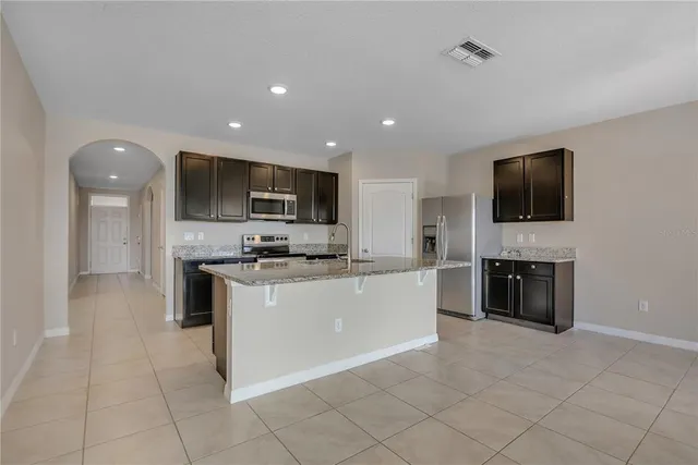 a large kitchen with kitchen island granite countertop a stove top oven a sink a refrigerator and a granite counter top