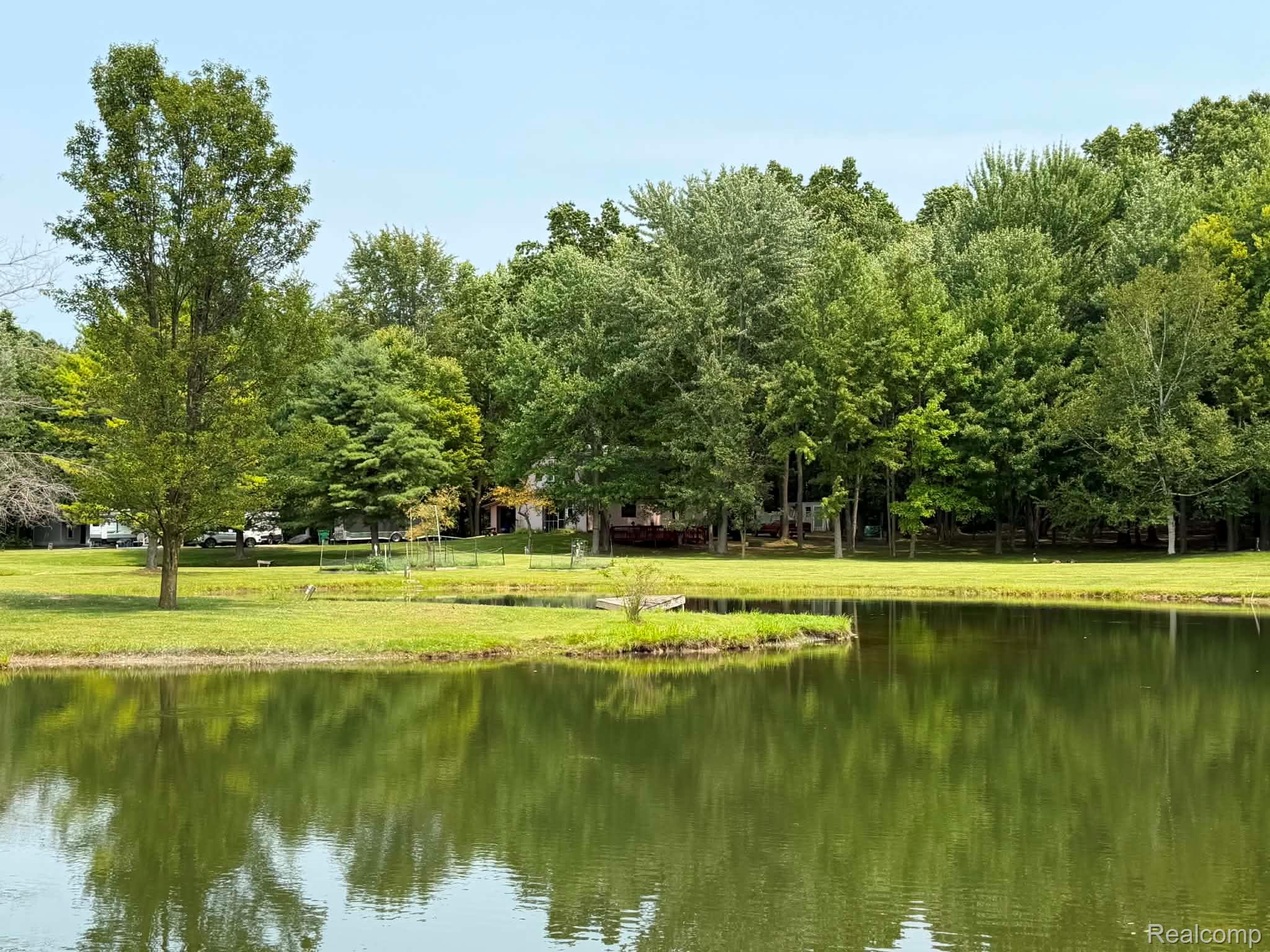 8110 North Latson Road Howell, MI 48855 - Photo 26 of 48 Waterfront property featuring expansive manicured grounds with mature shade trees, private pond frontage, and pastoral landscape