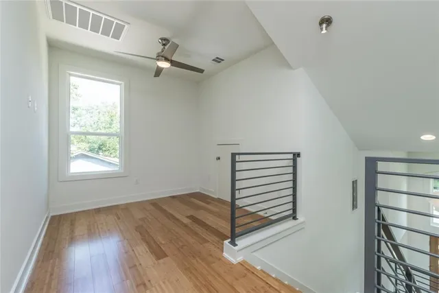a view of empty room with wooden floor and fan