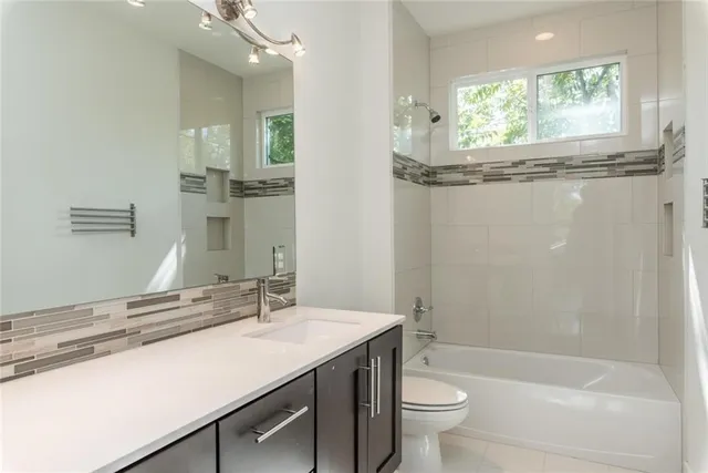 a bathroom with a granite countertop sink a toilet a mirror and shower