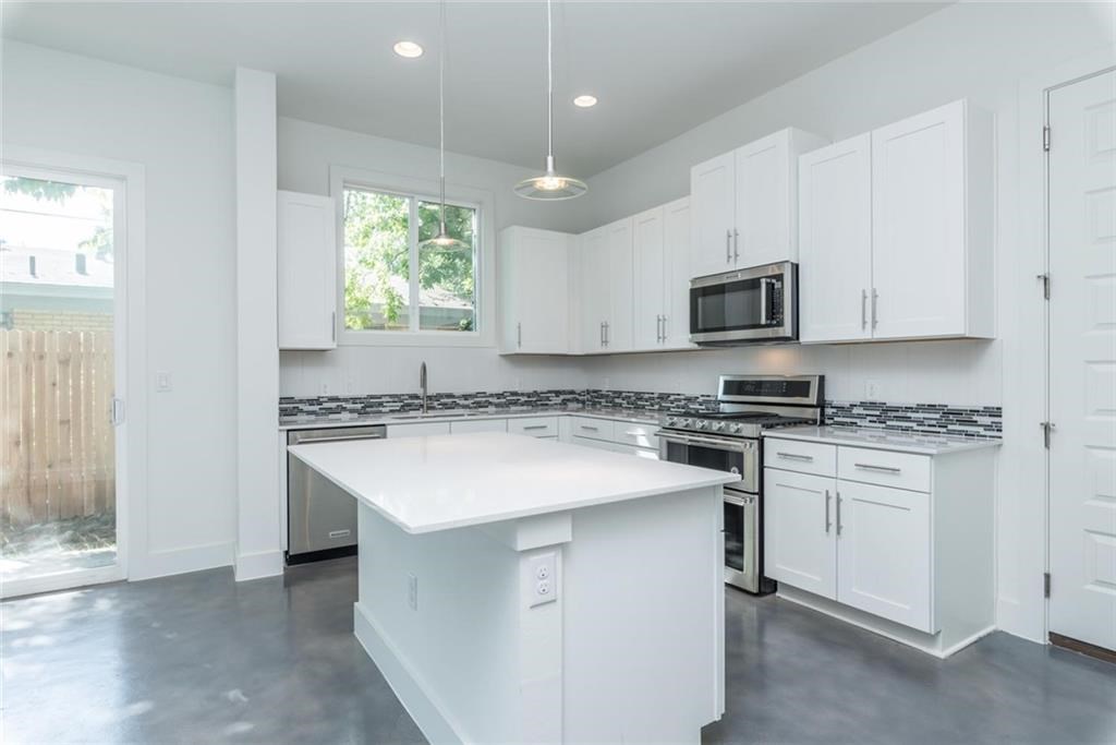 1403 Arcadia Avenue, Unit A Austin, TX 78757 - Photo 6 of 35 a kitchen with stainless steel appliances granite countertop a sink stove a refrigerator and a microwave