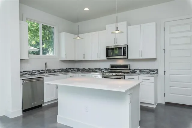 a kitchen with stainless steel appliances granite countertop a stove and a microwave