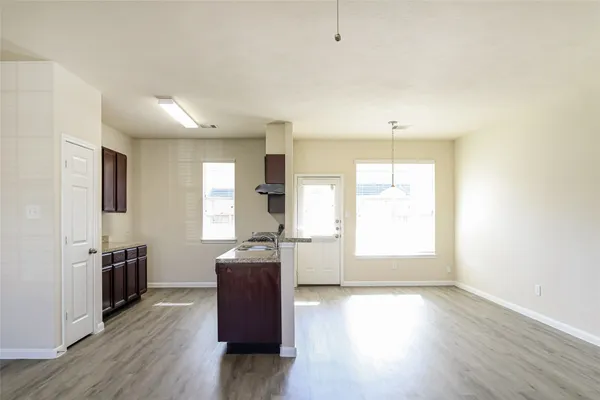 a kitchen with granite countertop a stove a sink wooden floor and white cabinets