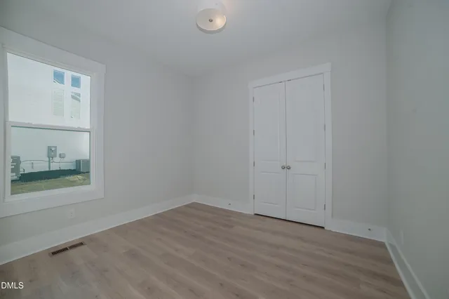 a view of an empty room with wooden floor and a window