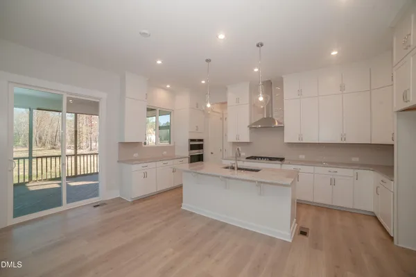 an empty room with wooden floor fireplace and windows