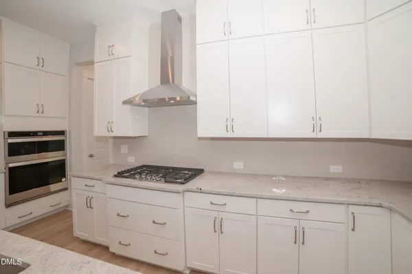 a kitchen with a stove a sink a refrigerator and white cabinets with wooden floor