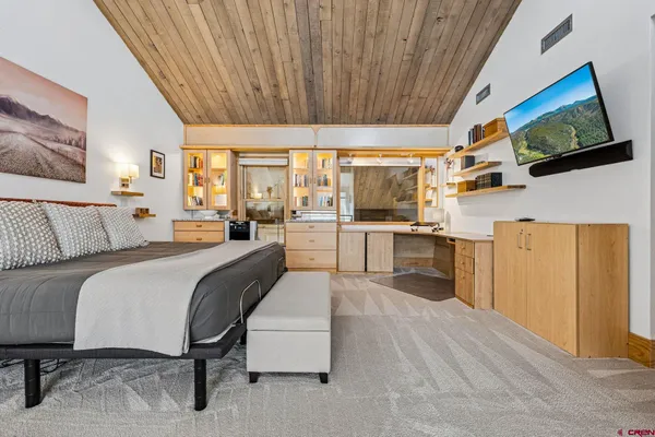 a spacious bedroom with a bed and a flat screen tv