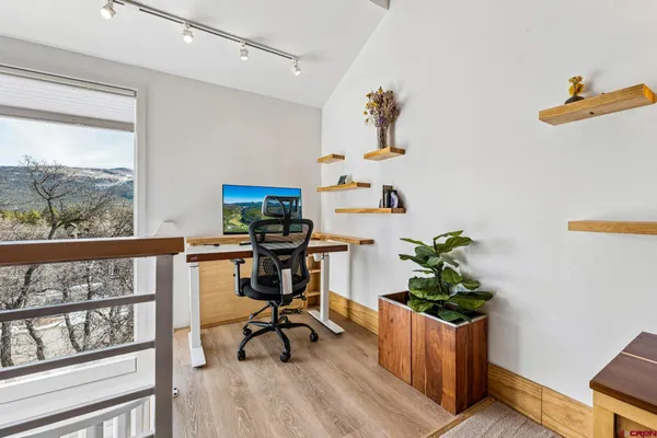 a view of a workspace with furniture and a window