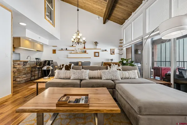 a living room with furniture kitchen view and a chandelier
