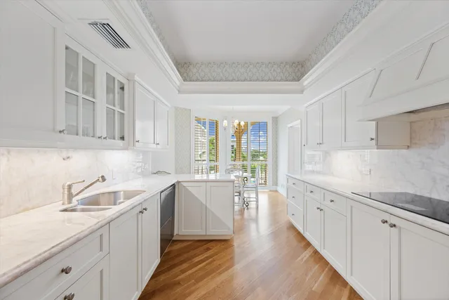 a kitchen with a sink dishwasher stove and white cabinets with wooden floor
