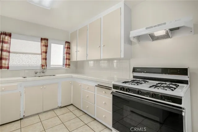 a white kitchen with sink and stove