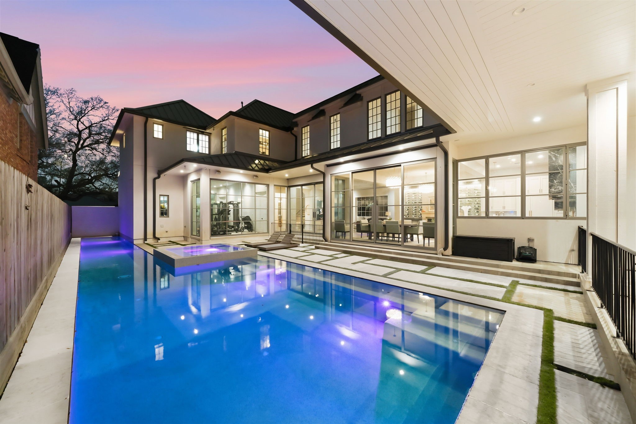 2615 Yupon Street Houston, TX 77006 - Photo 1 of 50 Located at 2615 Yupon St, this luxury custom estate showcases a contemporary backyard oasis with a heated pool, elevated hot tub, and sleek geometric pavers. Expansive steel and glass walls reveal the home gym and designer dining spaces, creating a seamless connection between the refined interior and the private outdoor retreat. 2022 construction features energy-efficient details and high-end finishes throughout this premier Inner Loop property.