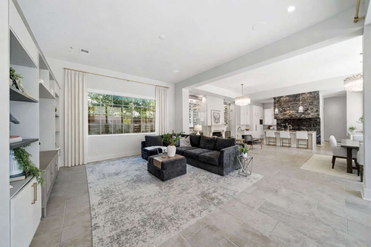 2615 Yupon Street Houston, TX 77006 - Photo 15 of 50 Expansive windows in the open-concept living area offer serene views of the backyard oasis and private pool. Custom built-in cabinetry provides ample storage and display space, while the stone tile flooring flows seamlessly into the gourmet kitchen and glass-enclosed wine room. High ceilings and designer lighting fixtures enhance the airy, luxurious feel of this primary entertainment hub.