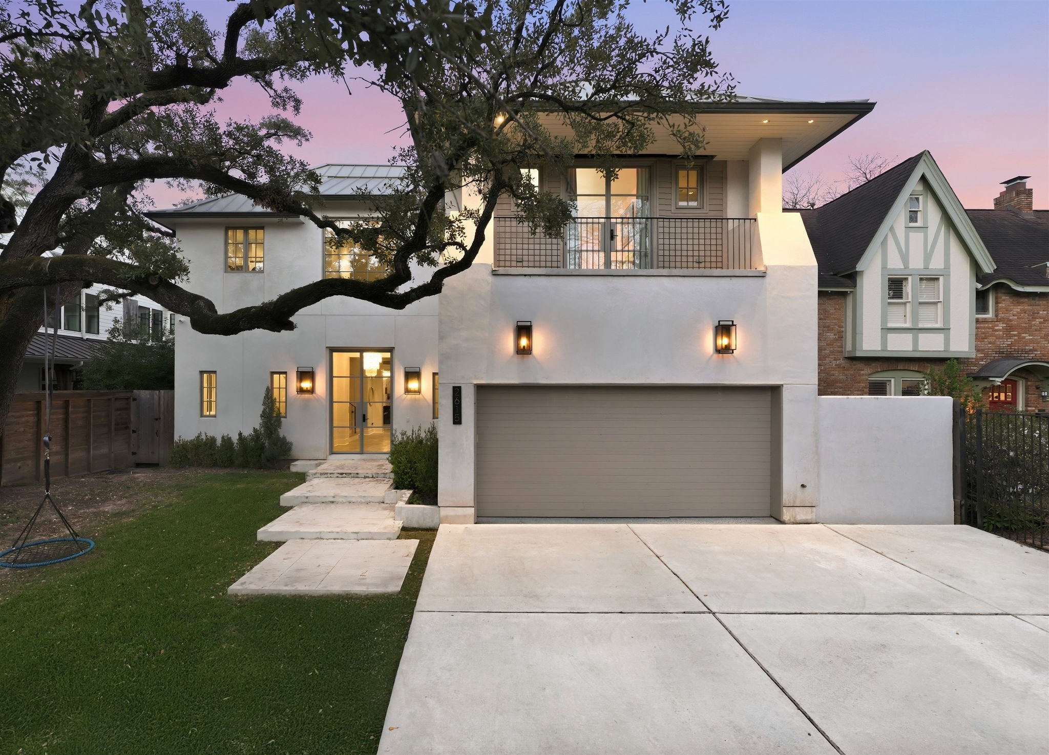 2615 Yupon Street Houston, TX 77006 - Photo 2 of 50 Boasting high curb appeal on a picturesque street, this 2022 contemporary estate at 2615 Yupon St features a striking stucco exterior framed by a grand canopy tree. A double-wide driveway leads to the sleek garage and modern floating concrete steps, while a private second-story balcony offers a refined vantage point. Steel and glass entry doors hint at the designer finishes found within this Montrose area gem.