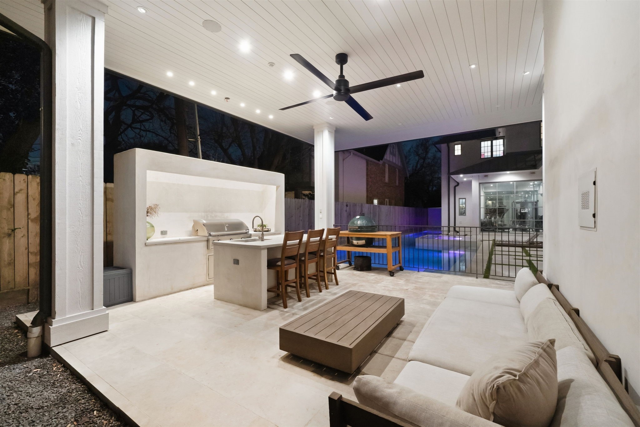 2615 Yupon Street Houston, TX 77006 - Photo 5 of 50 Summer kitchen excellence defines this expansive covered patio, featuring a sleek concrete island with bar seating and a professional-grade grill. The beadboard ceiling with recessed lighting and a modern fan overlooks the heated pool, providing a premier setting for open-air lounging and sophisticated entertaining.