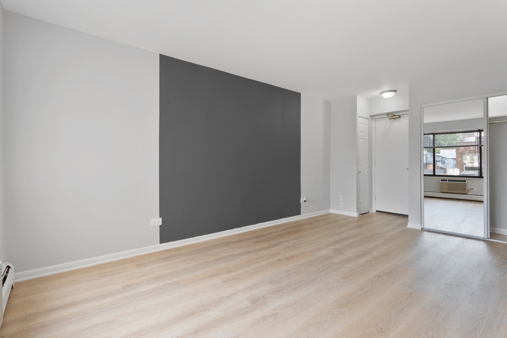 6758 North Sheridan Road, Unit 247 Chicago, IL 60626 - Photo 3 of 13 a view of an empty room with wooden floor and a kitchen