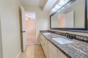 a bathroom with a granite countertop double vanity sink and a mirror