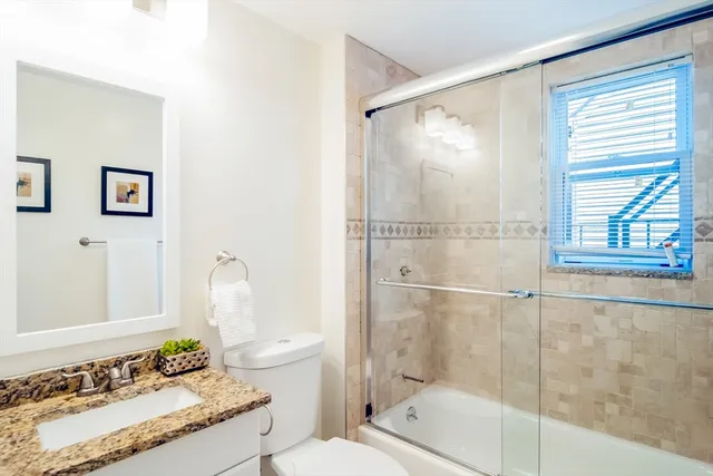 a bathroom with a granite countertop sink toilet and shower