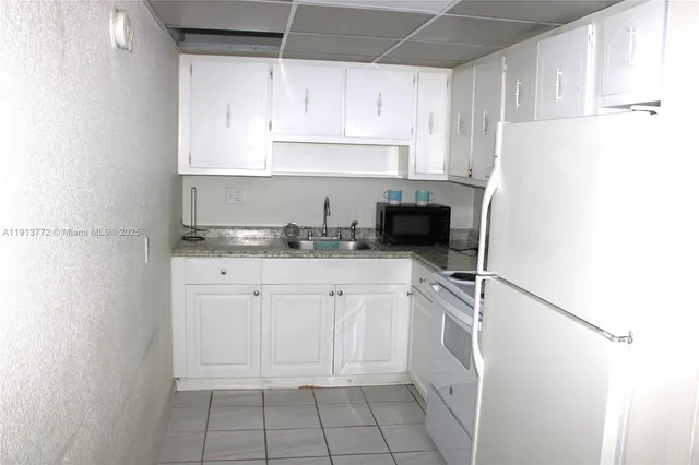 a kitchen with white cabinets and white appliances