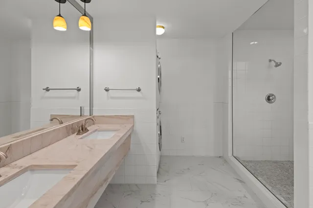 a bathroom with a granite countertop sink a mirror and a shower