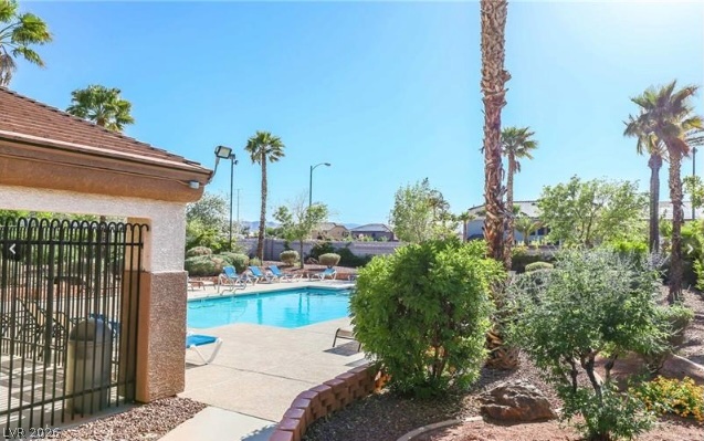 10247 Rising Tree Street Las Vegas, NV 89183 - Photo 6 of 7 A refreshing swimming pool awaits amidst lush landscaping and towering palms.