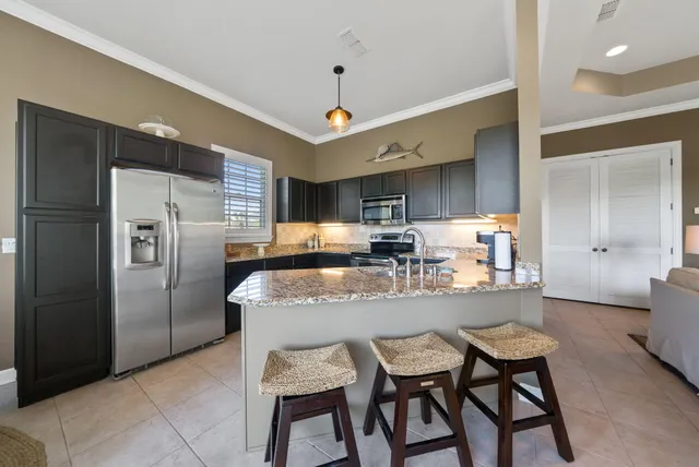 a kitchen with granite countertop a table chairs refrigerator and microwave
