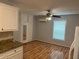 a view of empty room with wooden floor and fan