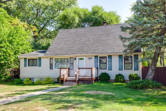 a view of a house with a yard plants and large tree