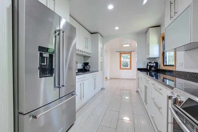 a large white kitchen with stainless steel appliances granite countertop a refrigerator and a stove
