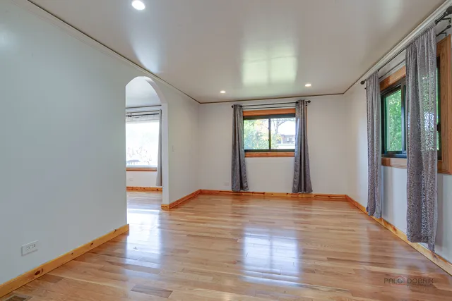 a view of an empty room with window and wooden floor